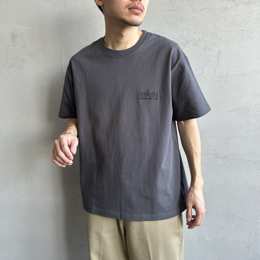 MANHATTAN PORTAGE [マンハッタンポーテージ] 別注 ランダムロゴ バックプリントTシャツ [25SSMP-IN66-JF] CHARCOAL &&モデル身長：168cm 着用サイズ：L&&