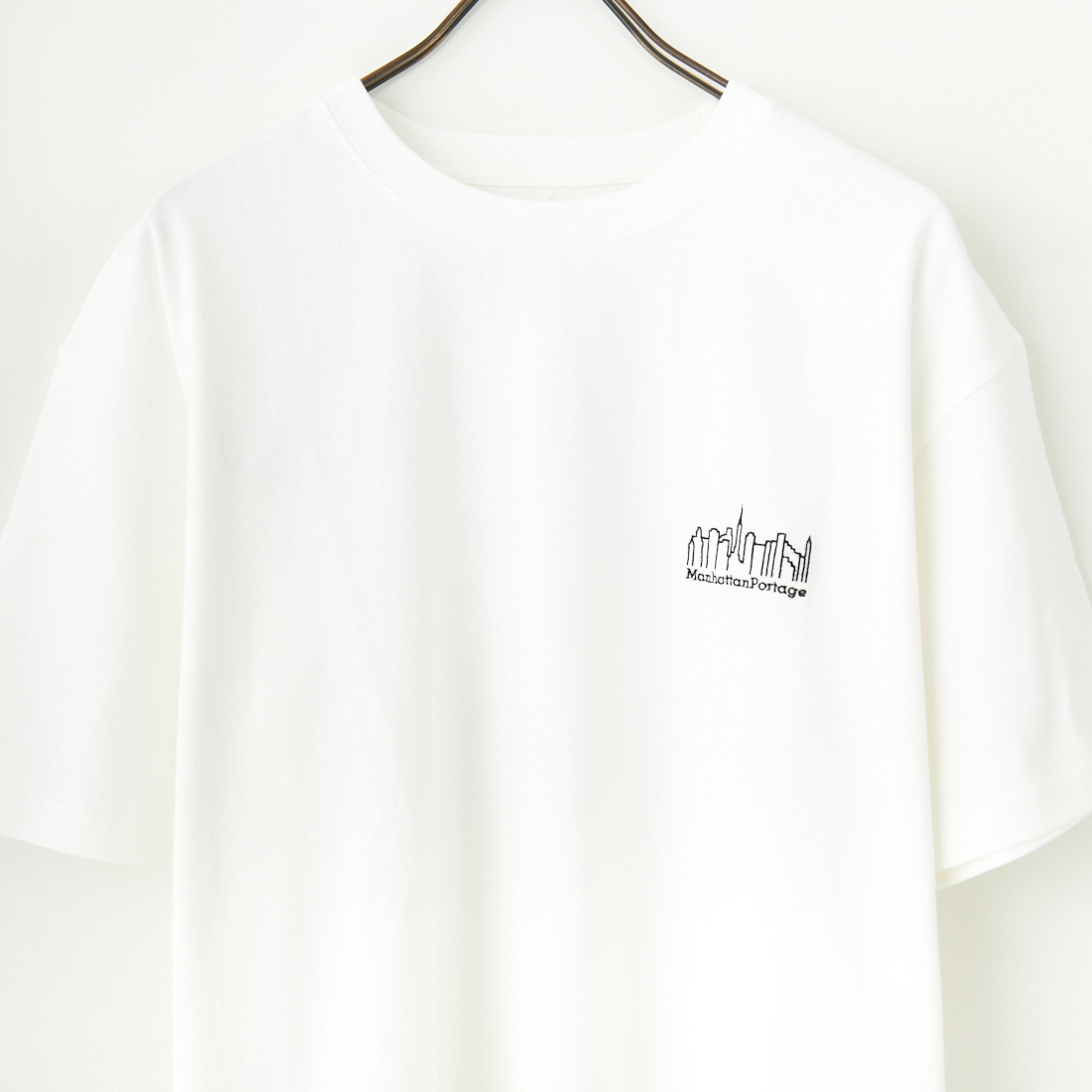 MANHATTAN PORTAGE [マンハッタンポーテージ] 別注 ランダムロゴ バックプリントTシャツ [25SSMP-IN66-JF] WHITE