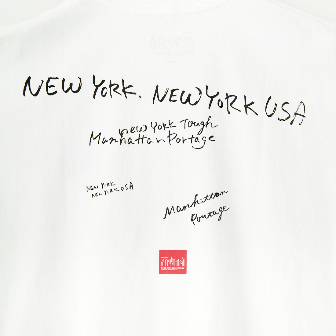 MANHATTAN PORTAGE [マンハッタンポーテージ] 別注 ランダムロゴ バックプリントTシャツ [25SSMP-IN66-JF] WHITE
