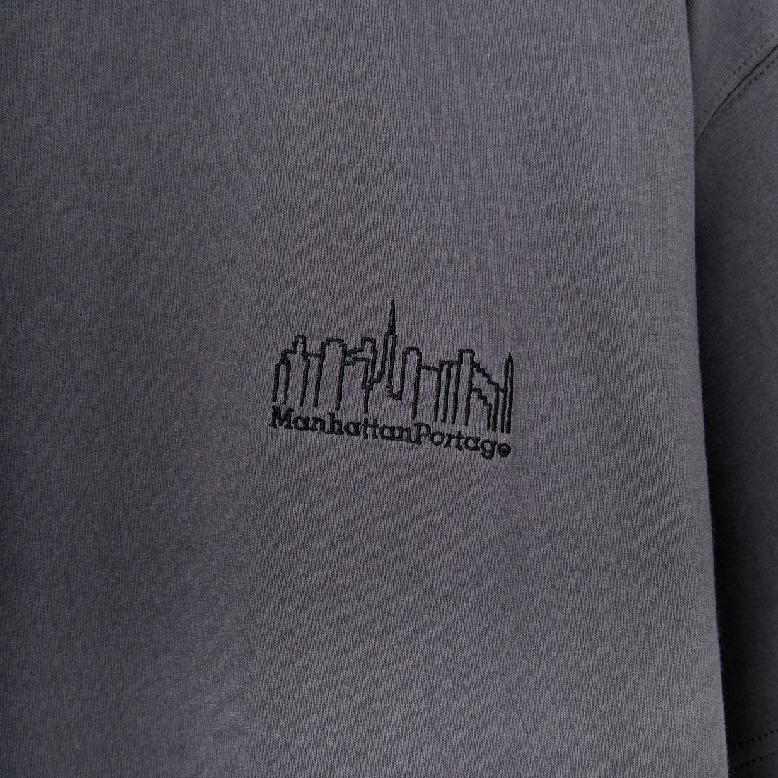 MANHATTAN PORTAGE [マンハッタンポーテージ] 別注 ランダムロゴ バックプリントTシャツ [25SSMP-IN66-JF] CHARCOAL