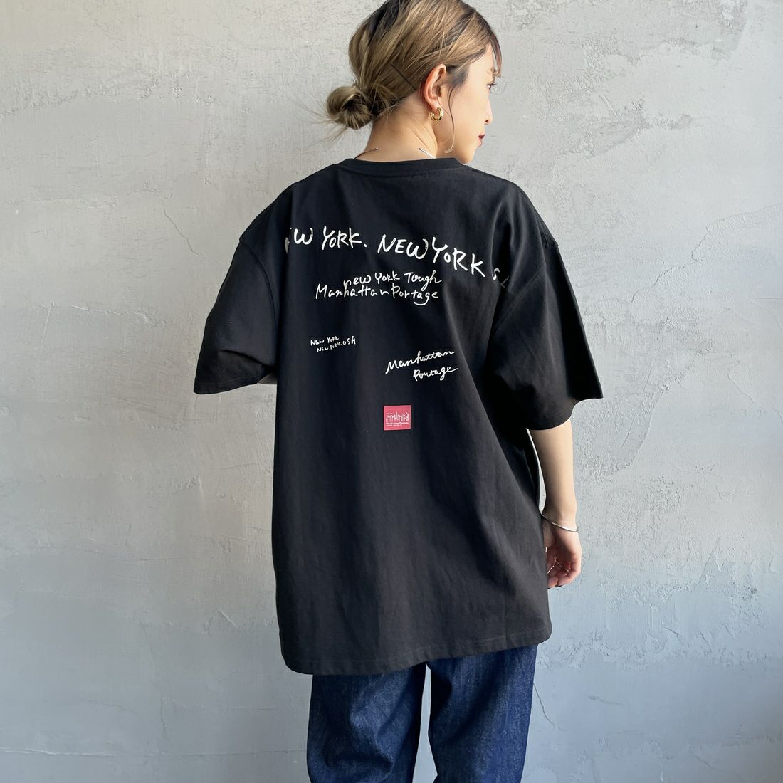 MANHATTAN PORTAGE [マンハッタンポーテージ] 別注 ランダムロゴ バックプリントTシャツ [25SSMP-IN66-JF] BLACK &&モデル身長：150cm 着用サイズ：S&&