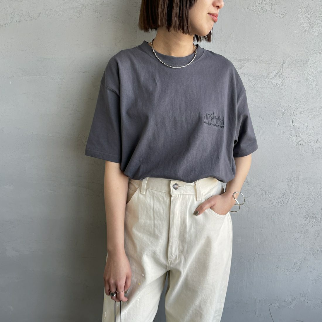 MANHATTAN PORTAGE [マンハッタンポーテージ] 別注 ランダムロゴ バックプリントTシャツ [25SSMP-IN66-JF] CHARCOAL &&モデル身長：159cm 着用サイズ：S&&