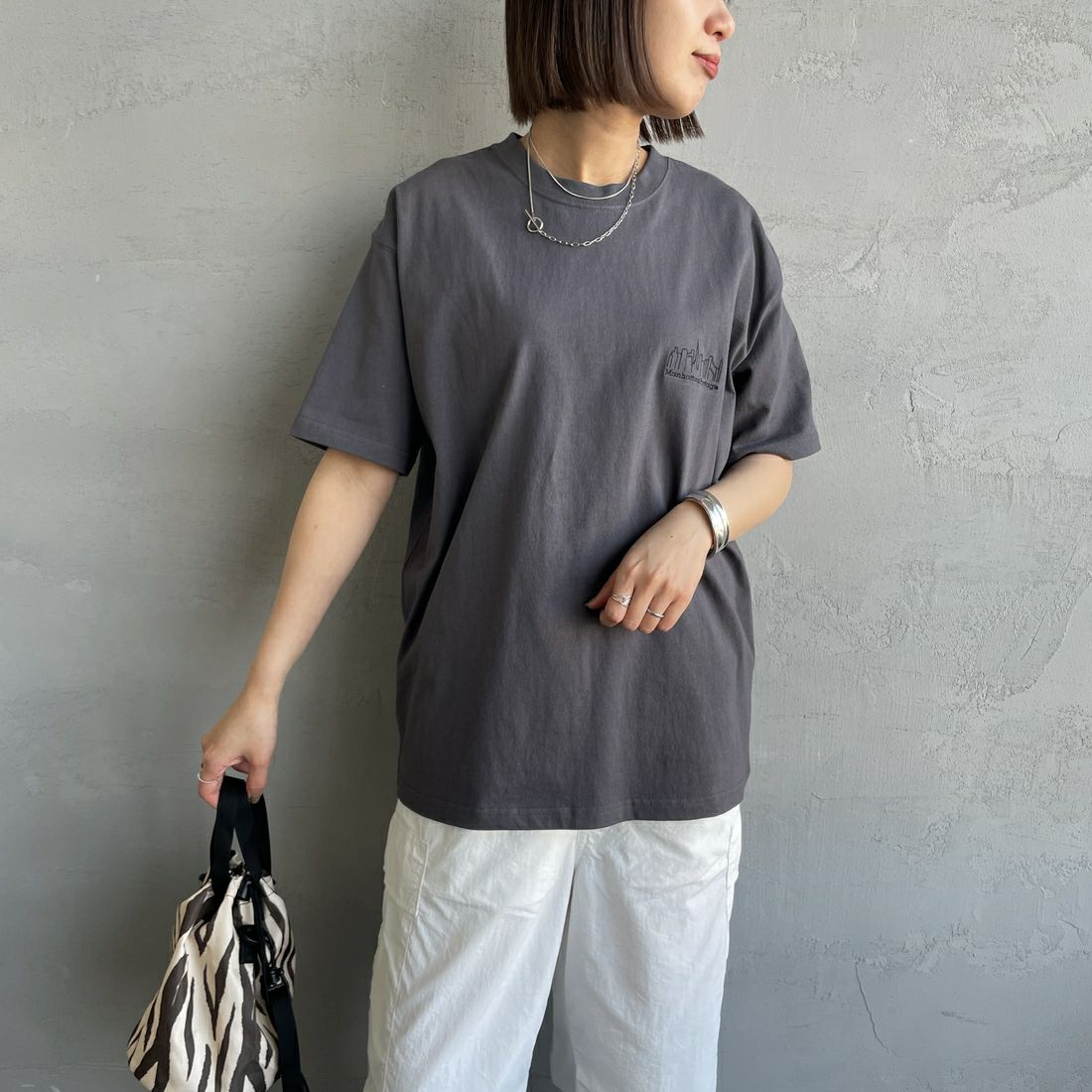 MANHATTAN PORTAGE [マンハッタンポーテージ] 別注 ランダムロゴ バックプリントTシャツ [25SSMP-IN66-JF] CHARCOAL &&モデル身長：159cm 着用サイズ：S&&