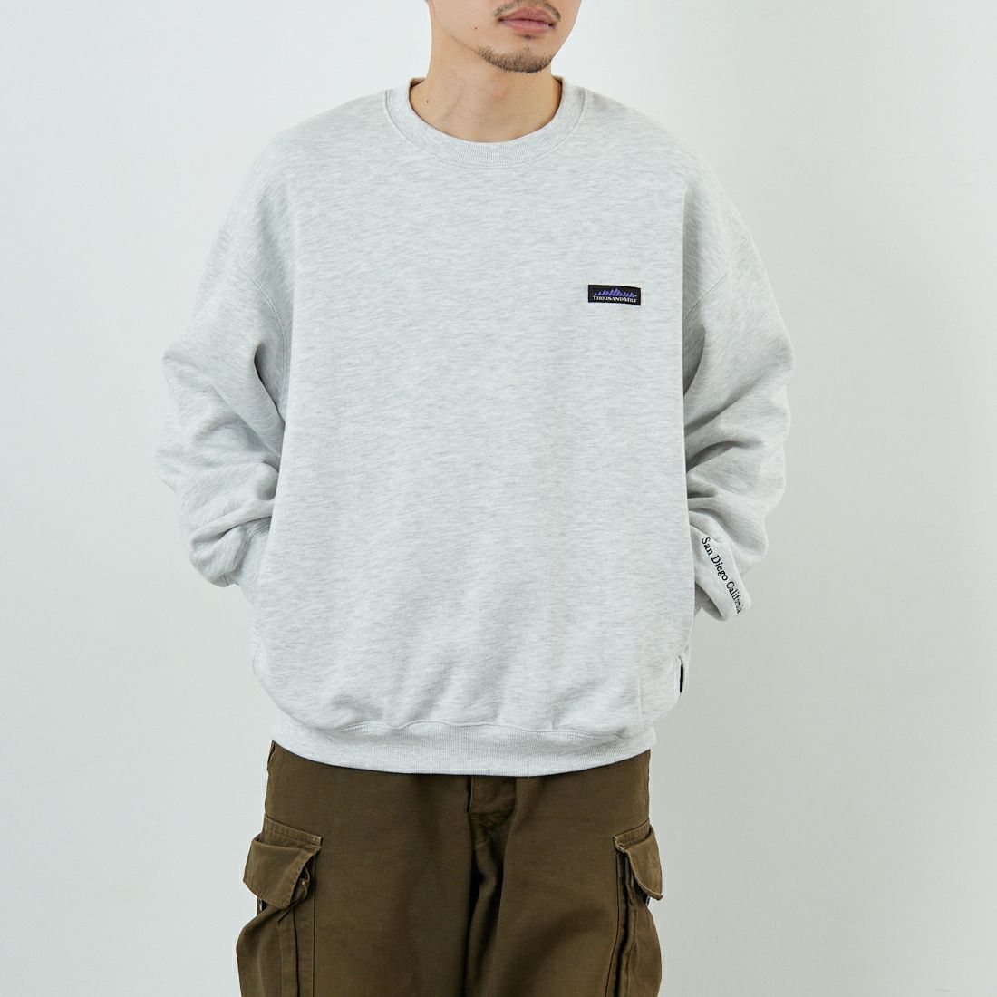 THOUSAND MILE [サウザンド マイル] 別注 ワンポイントロゴ クルーネックスウェット [TM252UK50510-JF] 11 LT.GRAY &&モデル身長：168cm 着用サイズ：M&&