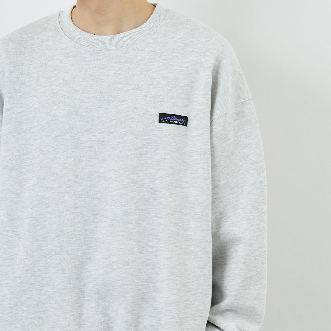 THOUSAND MILE [サウザンド マイル] 別注 ワンポイントロゴ クルーネックスウェット [TM252UK50510-JF] 11 LT.GRAY &&モデル身長：168cm 着用サイズ：M&&